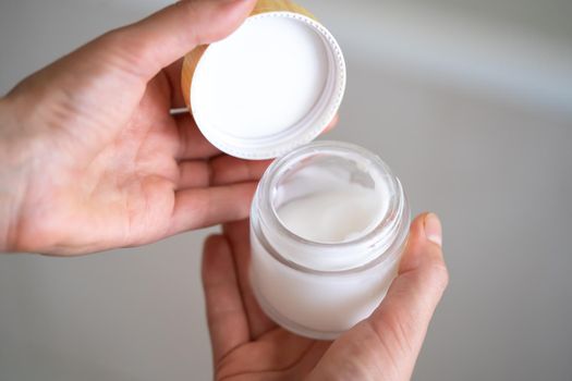 Young female hands hold a jar of moisturizing cream to maintain health, softness of the skin, the woman takes care of her health and beauty.