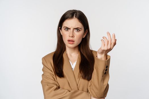 Portrait of confused businesswoman, staring puzzled and frustrated, cant understand smth, standing in suit over white background.