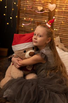 A girl hugs a bear toy in a Christmas cap bear Christmas kid girl cute, In the afternoon female smiling in lovely sitting sweet, adorable plush. Pillow woman care, blanket wake
