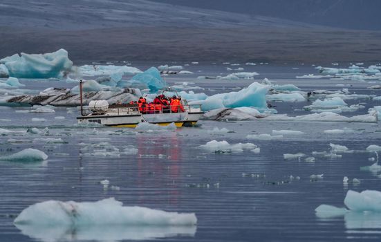 Icebergs in Jokulsarlon and unrecognizable tourists boat