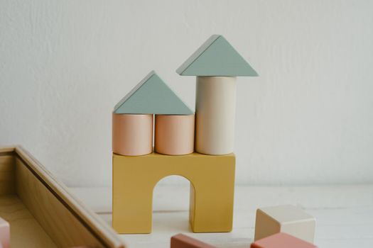 Wooden building blocks - home concept. Toy castle made of bright building blocks on white background. Composition of colorful educational baby kid wood toys. Child development concept.