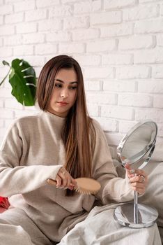 Valentine's day, Women's day. Brunette young Woman celebrating valentines day, sitting on the bed brushing hair looking at the mirror