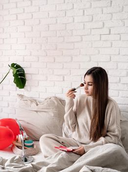 Valentine's day, Women's day. Brunette young Woman celebrating valentines day, sitting on the bed making up