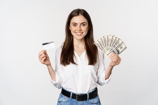Portrait of woman standing with cash and credit card, concept of money, microcredit and loans, standing over white background happy.
