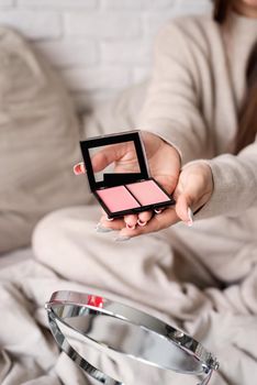 Valentine's day, Women's day. Woman sitting in bed holding powder blusher