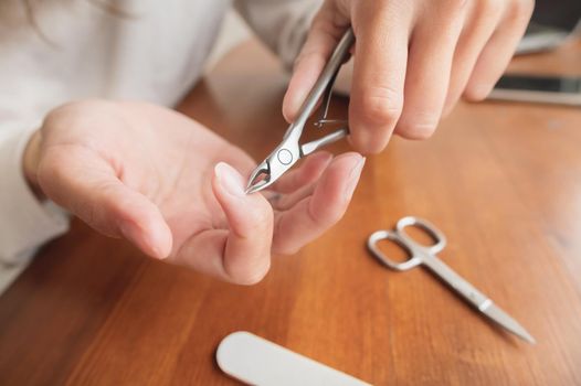 Close-up of hand of caucasian young woman doing manicure at home with nail supplies
