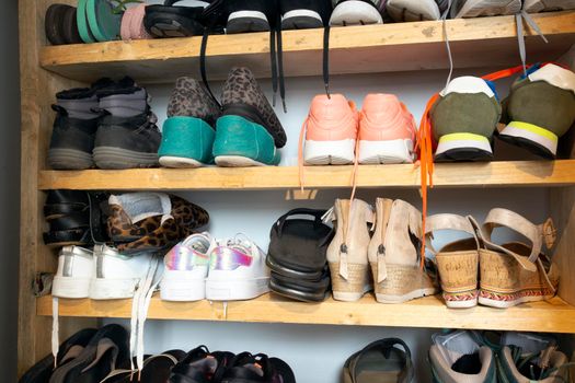 Collection of different shoes in shoe rack for storage, messy and needs organize, wardrobe with shelfs in house interior design stylish decoration close up