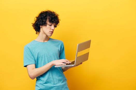 curly guy with laptop work online finance yellow background. High quality photo