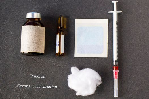 Omicron, corona virus variation. Vaccine ampule, needle and cotton on the gray background, vaccine injection