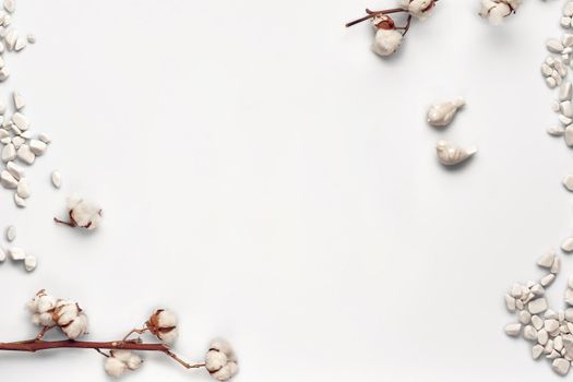 Flowers of cotton, sea stones and two small ceramic birds isolated on white background. Close up, copy space for your text or images. Mock up for your advertising. Top view, flat lay