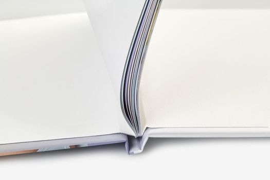 Open photo book with hardback and blank pages on white studio background. Close up, copy space. Mock up, template