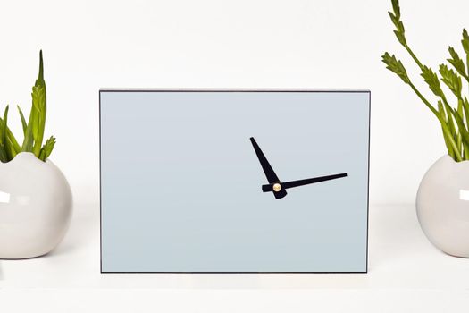 Watch with black hands without a dial surrounded by vases with green plants or flowers, isolated on white. Close up, copy space for your text or images. Empty blank mock up. Branding area, decor