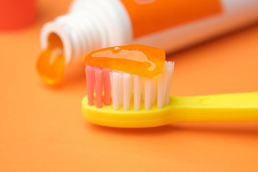orange color child tooth brush with paste.