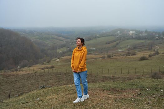 The girl walks in a meadow high in the mountains. Spectacular views of the valley of the clouds.