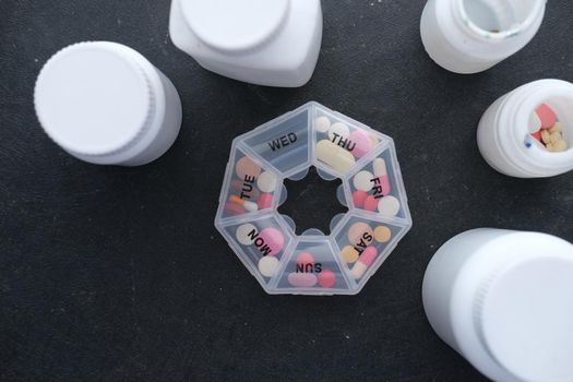 top view of pill box and container on black .