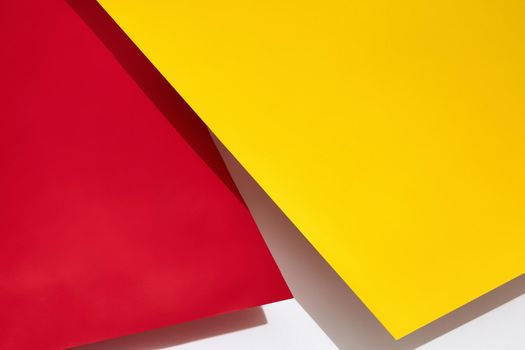 Red and yellow shadow-casting sheets of paper or stands above white surface. Advertising, branding area. Close up, copy space. Top view, mock up