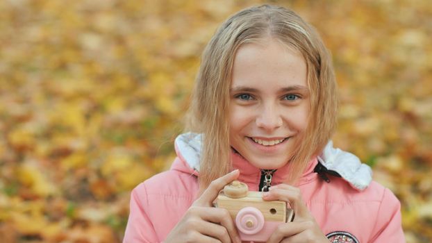 Teenage girl with toy cameras takes pictures in the autumn park