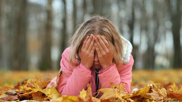 Teenage girl crying in the autumn foliage in the park