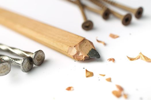 Low Angle Close up of a Carpenter's Pencil with Sharpening Shavings, Framing Nails and Deck Screws on a white background. High quality photo