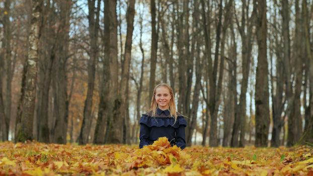 A teenage girl is sitting in an autumn park