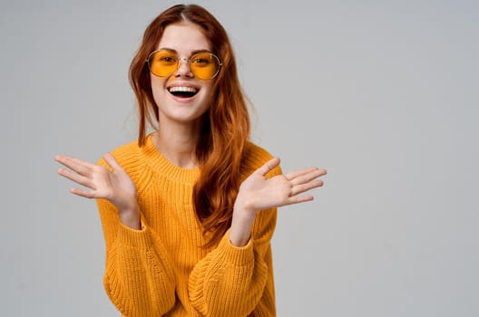 pretty woman in a yellow sweater fashion glasses light background. High quality photo