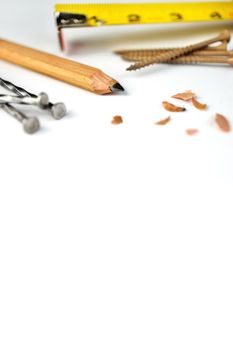 Low Angle Close up of a Carpenter's Pencil with Sharpening Shavings, Tape Measure, Framing Nails and Deck Screws on a white background. High quality photo