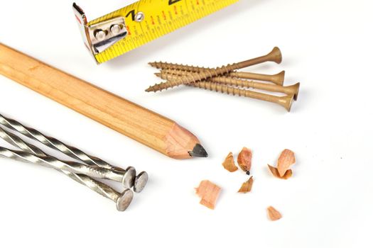 High Angle Close up of a Carpenter's Pencil with Sharpening Shavings, Tape Measure, Framing Nails and Deck Screws on a white background. High quality photo