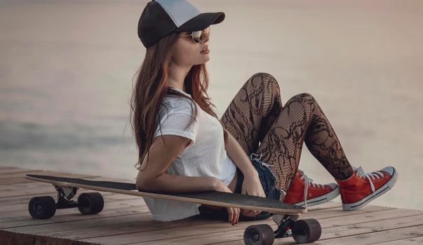 Beautiful and fashion young woman posing with a skateboard