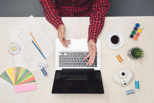 Male fashion designer is working or counting on his office table. Top view