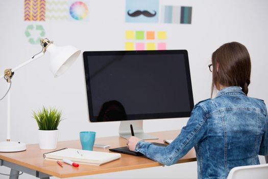 Woman working at desk In a creative office, using a computer 