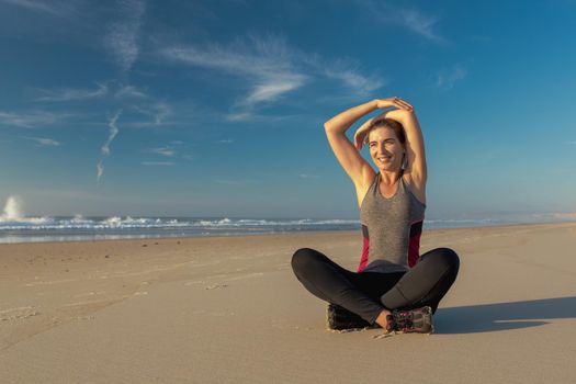 Shoot of a beautiful woman making stretching exercises in the beach