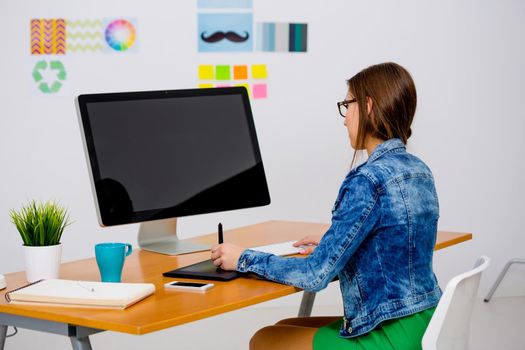 Woman working at desk In a creative office, using a computer 