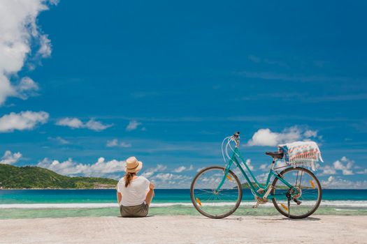 Woman and her bicycle at teh beach in Seychelles