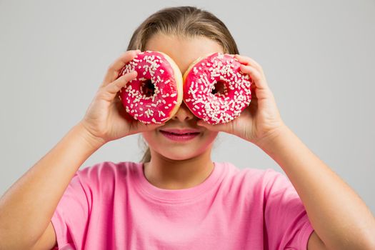 Studio portrait of a beautiful little girl looking through a donut