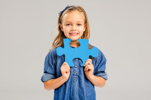 Beautiful little girl holding a blue Puzzle