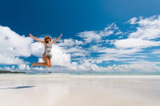 Beautiful woman jumping on the wonderful beach of Praslin, Seychelles