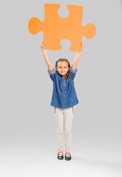 Beautiful little girl holding a big blue Puzzle