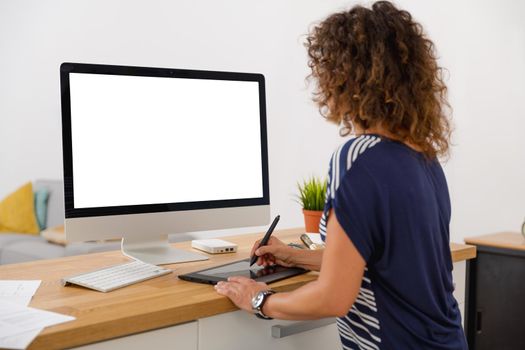 Middle age designer working on a desktop at her office