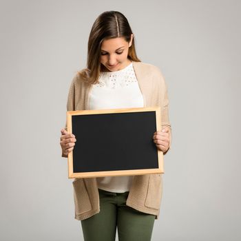 Beautiful and happy woman holding a chalkboard, with copy-space