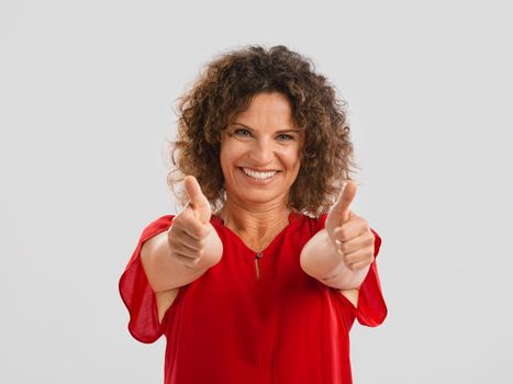 Portrait of a smiling middle aged brunette with thumbs up