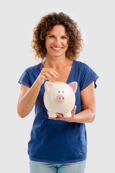 Portrait of a happy middle aged woman puting some money on a Piggybank