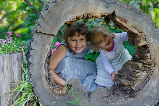 Two funny little girls having fun with a sleigh in beautiful park. High quality photo