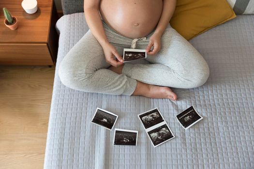Pregnant woman looking to the picture of the ultrasound, Prenatal health care concept.