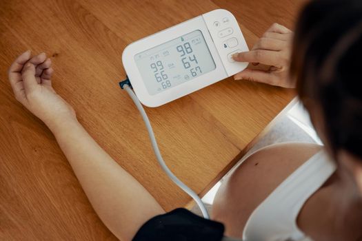 Pregnant woman measuring her blood pressure during the third trimester