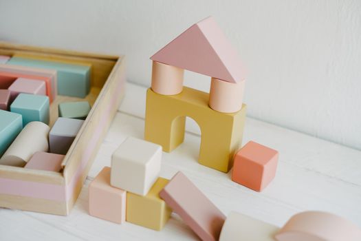 Wooden building blocks - home concept. Toy castle made of bright building blocks on white background. Composition of colorful educational baby kid wood toys. Child development concept.