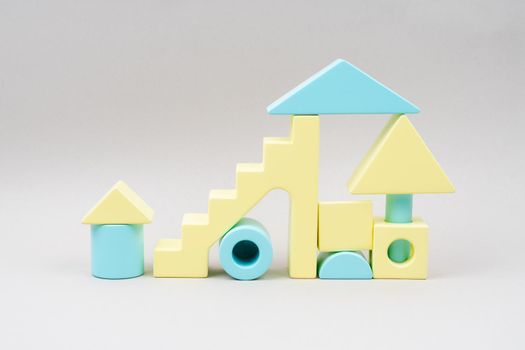 Children's wooden construction kit in blue and yellow colors. Eco-friendly toys on a gray background. The natural material of the cubes.