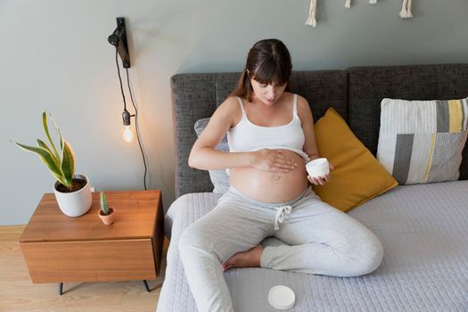 Pregnant woman applying stretch mark cream in her belly