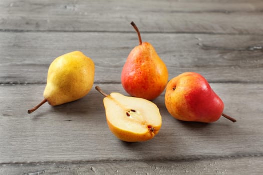 Four pears, one cut in half, on gray wood desk.