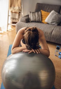 Pregnant woman working out at home doing exercises on a fitball. Keeping in good shape while waiting for baby
