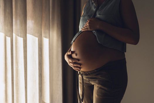 Pregnant woman touching her belly by the morning